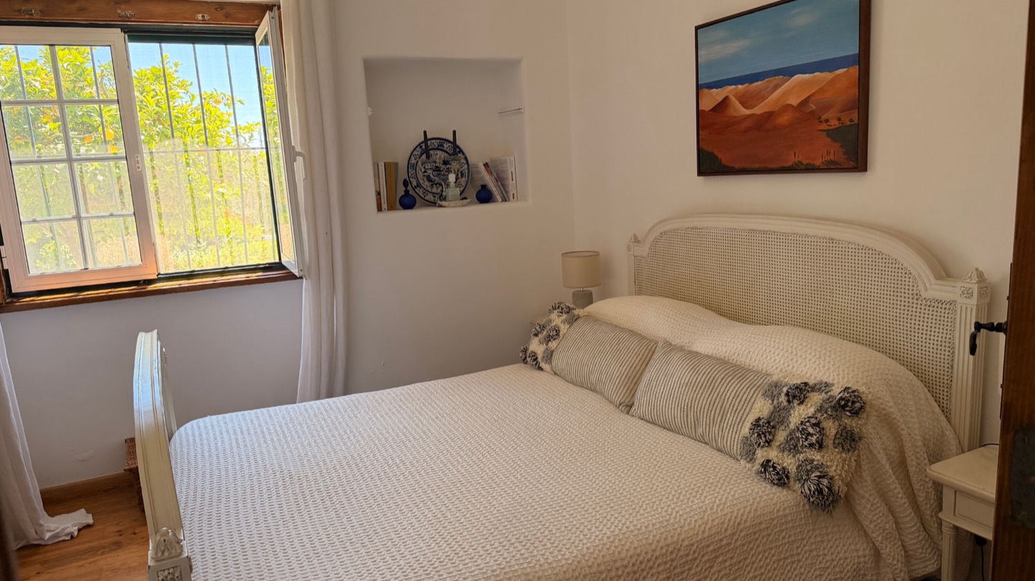 A calm double bedroom with a cane headboard at the quinta
