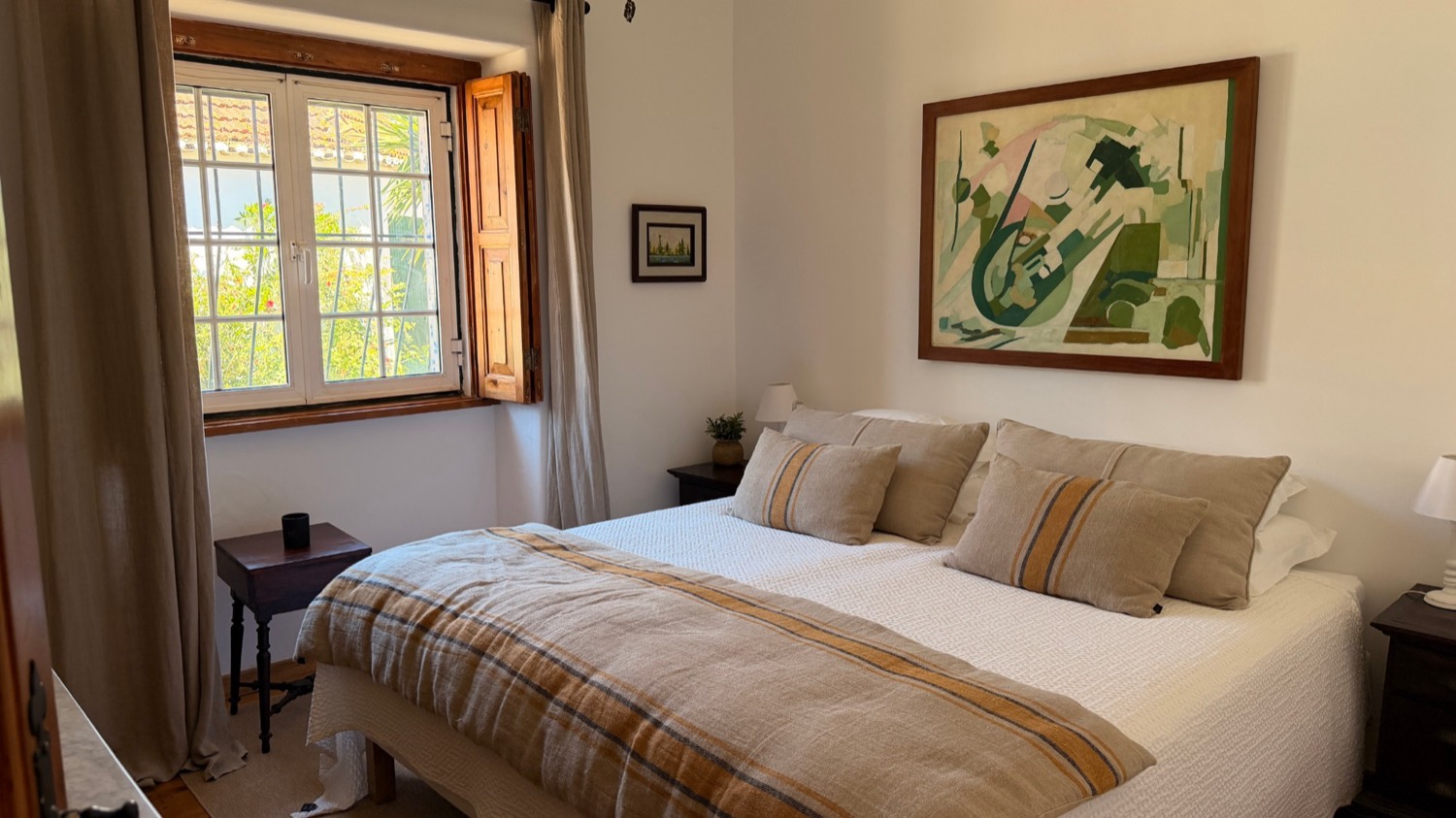 A bright double bedroom with linen bedding and garden light