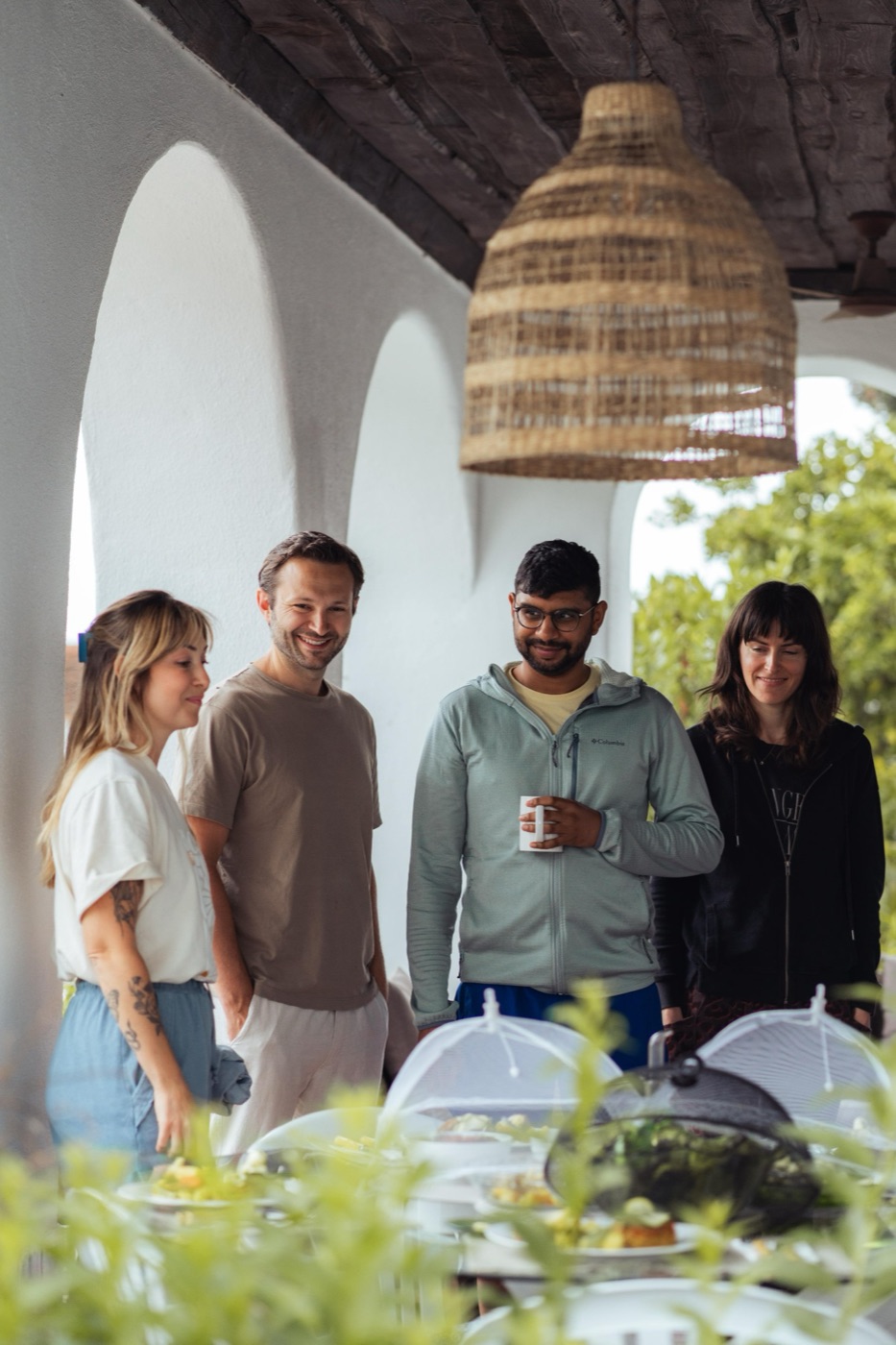 Guests gathering at the covered lunch table under the arches