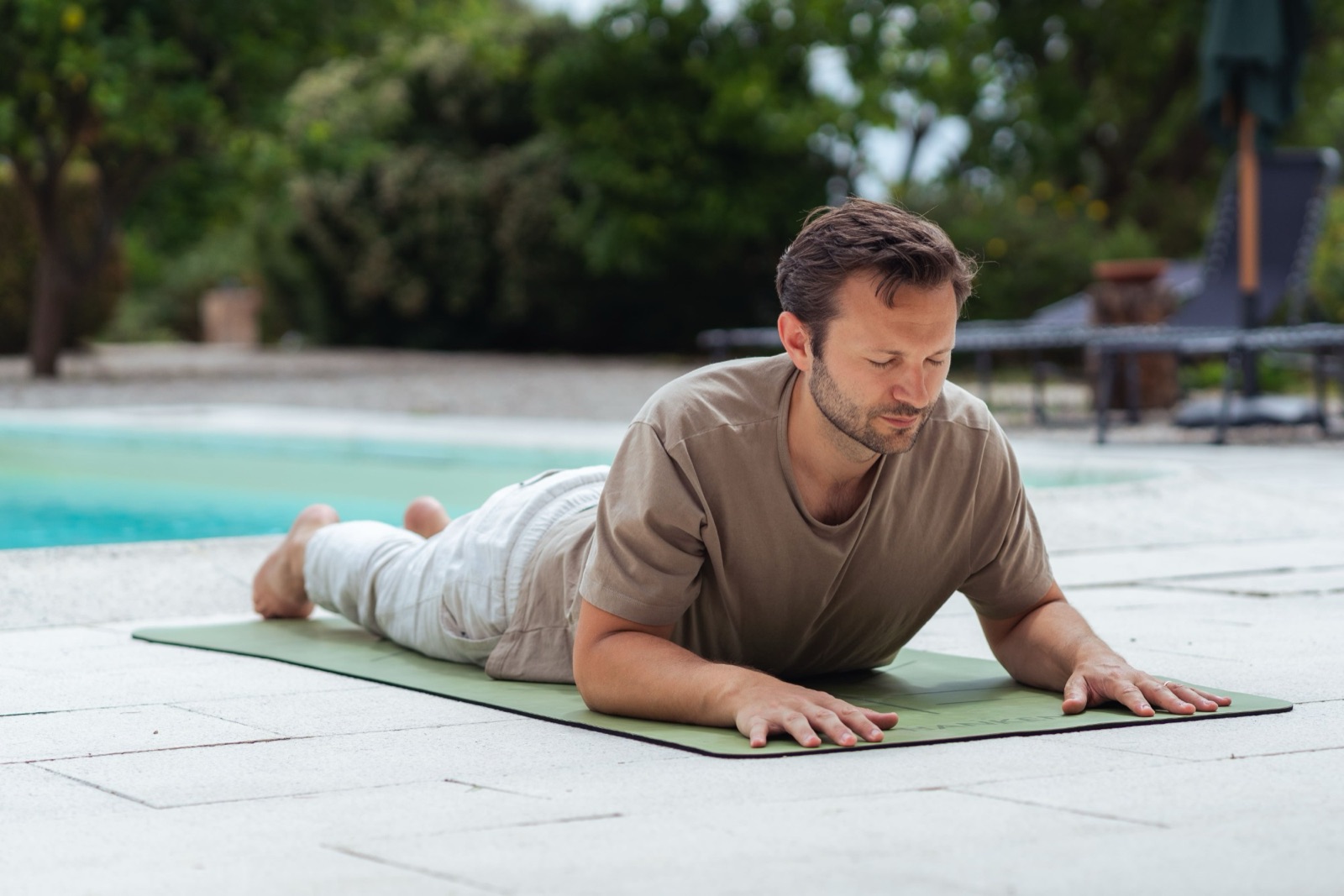 A guest practising a gentle yoga pose beside the pool on retreat